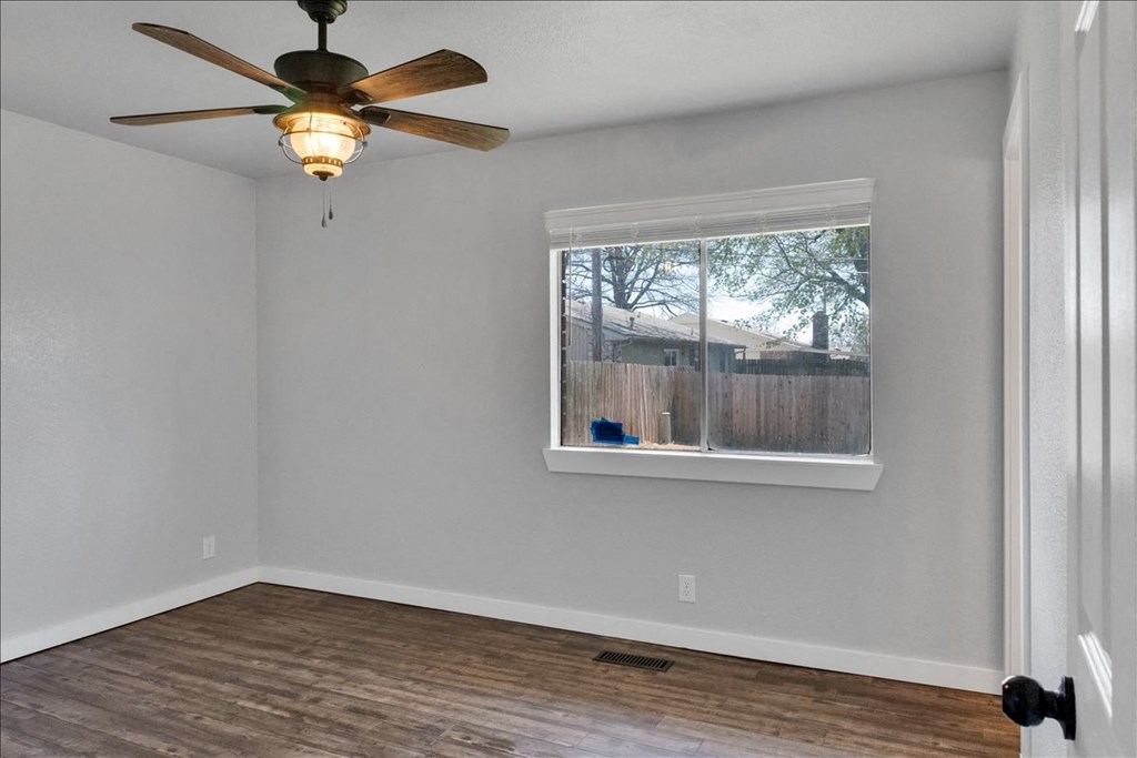 an empty room with a window and a ceiling fan