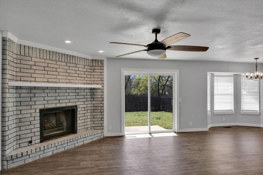 a living room with a brick fireplace and a ceiling fan