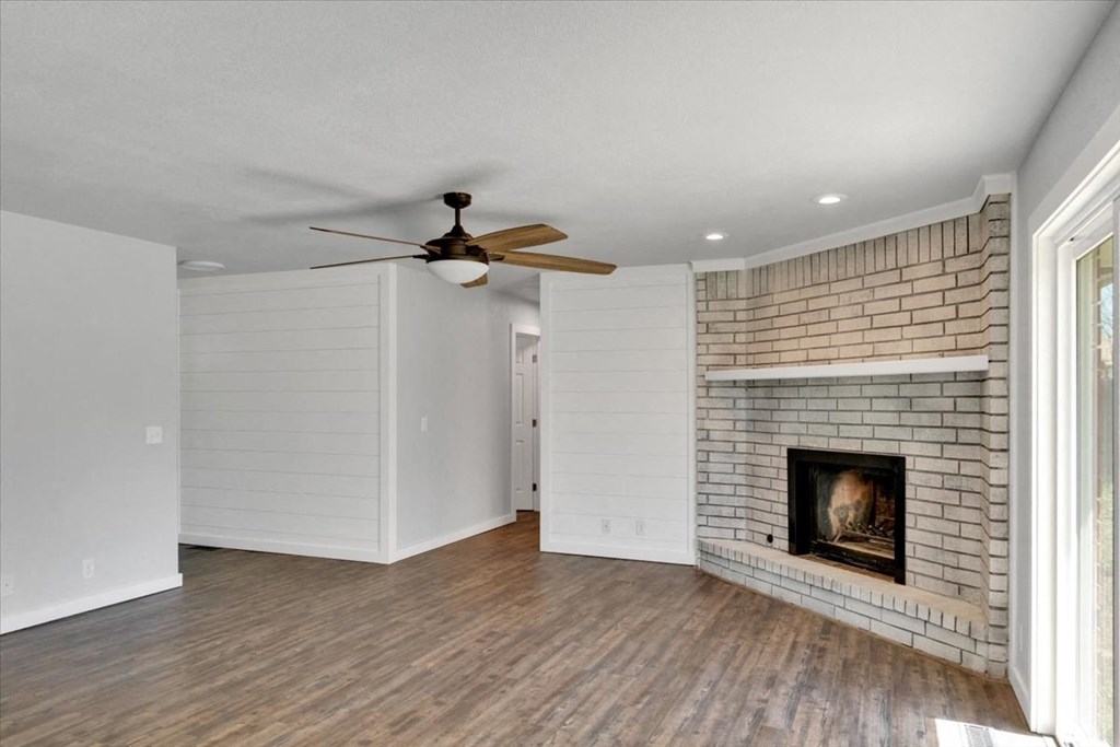a living room with a brick fireplace and a ceiling fan