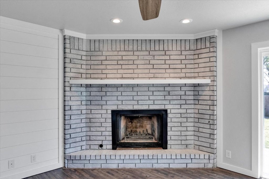 a white brick fireplace in a living room with a wooden floor