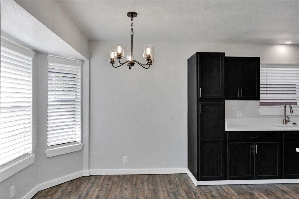 the kitchen and dining room of a new home with black cabinets