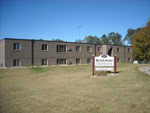 A large building with a sign that says Brickstone Apartments in front of it.