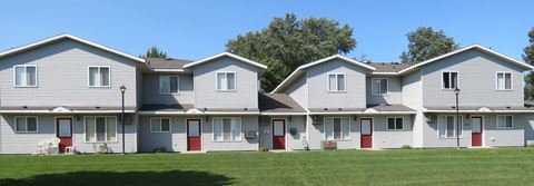 a row of houses with red doors and white siding