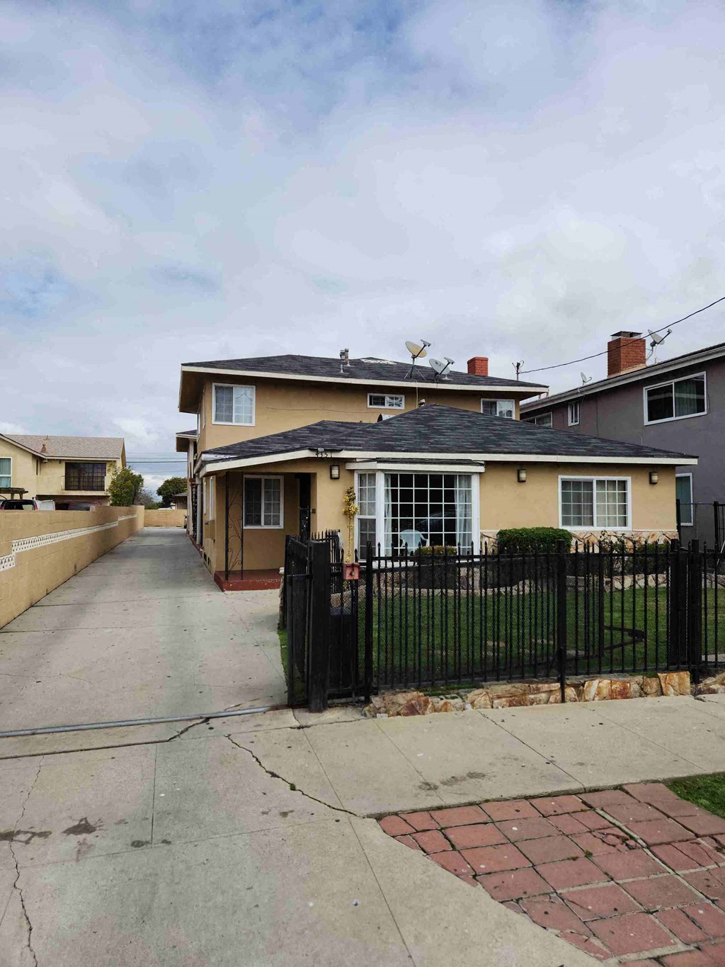 the front of a house with a yard and a black fence