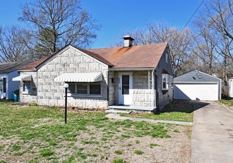 a small white house with a yard and a sidewalk