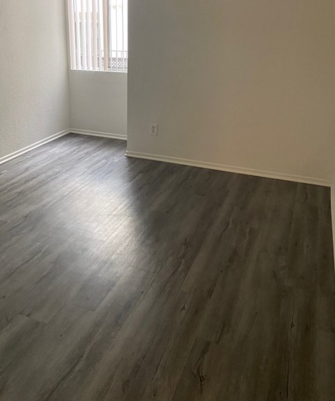 an empty living room with wooden floors and a window