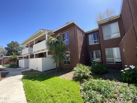 Apartment complex with a white fence and green grass in front.