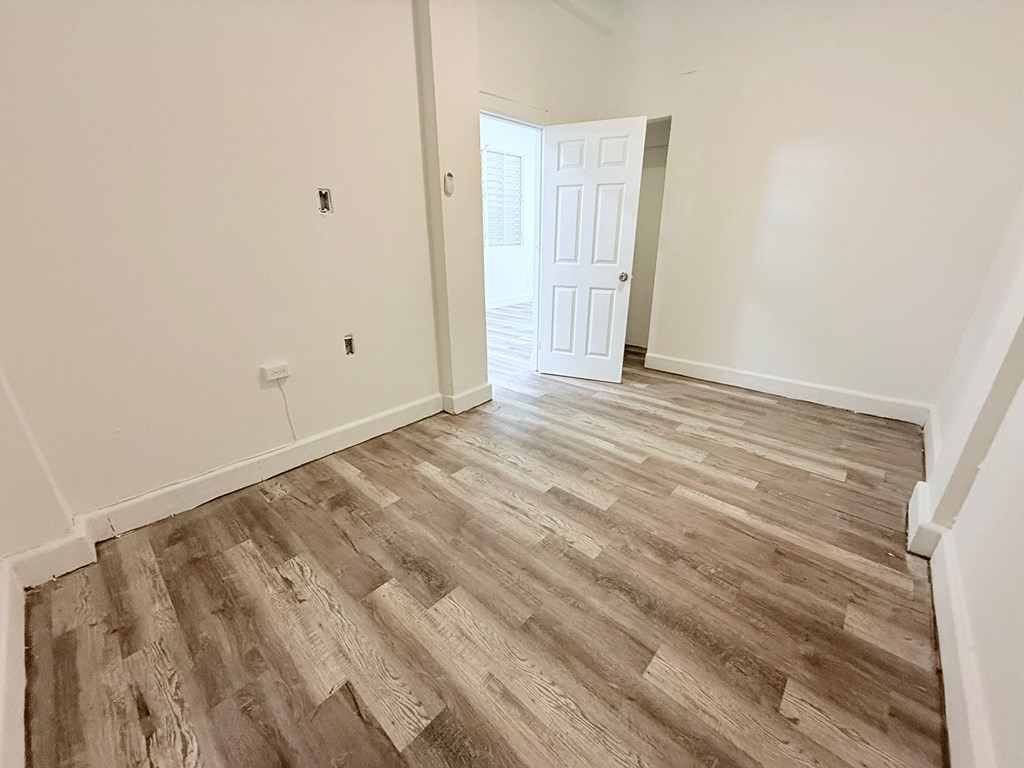 A room with a white door and wooden flooring.