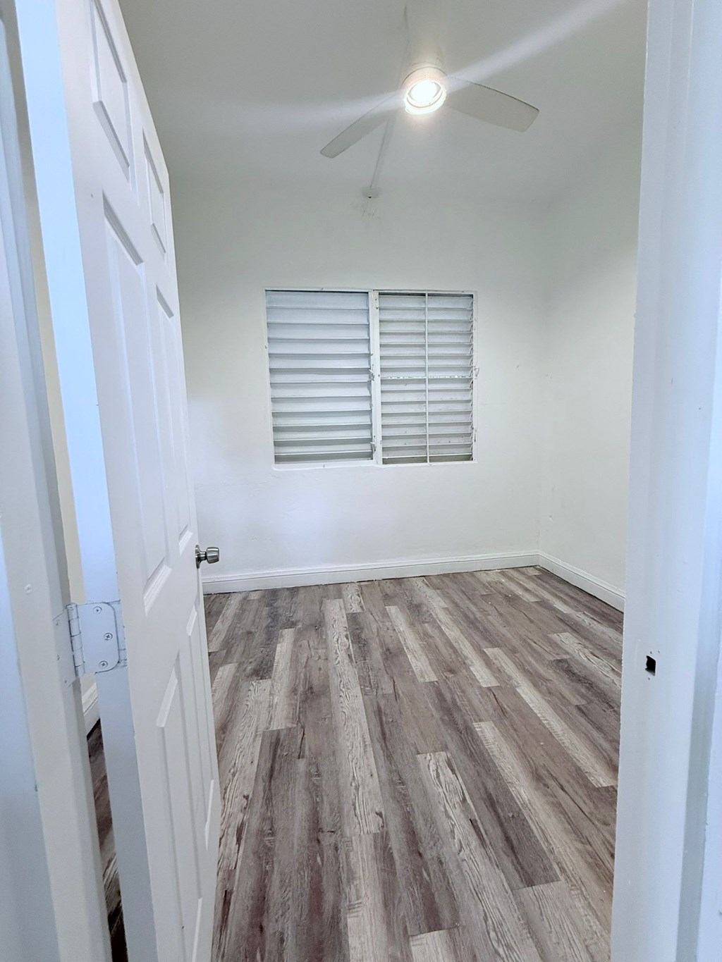 A room with a wooden floor and a ceiling fan.
