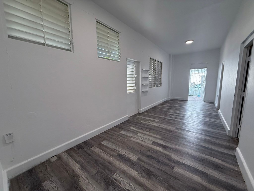 A long, empty hallway with wooden floors and white walls.