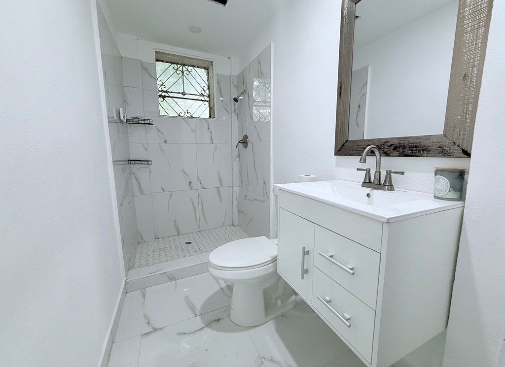 A white bathroom with a toilet, sink, and shower.