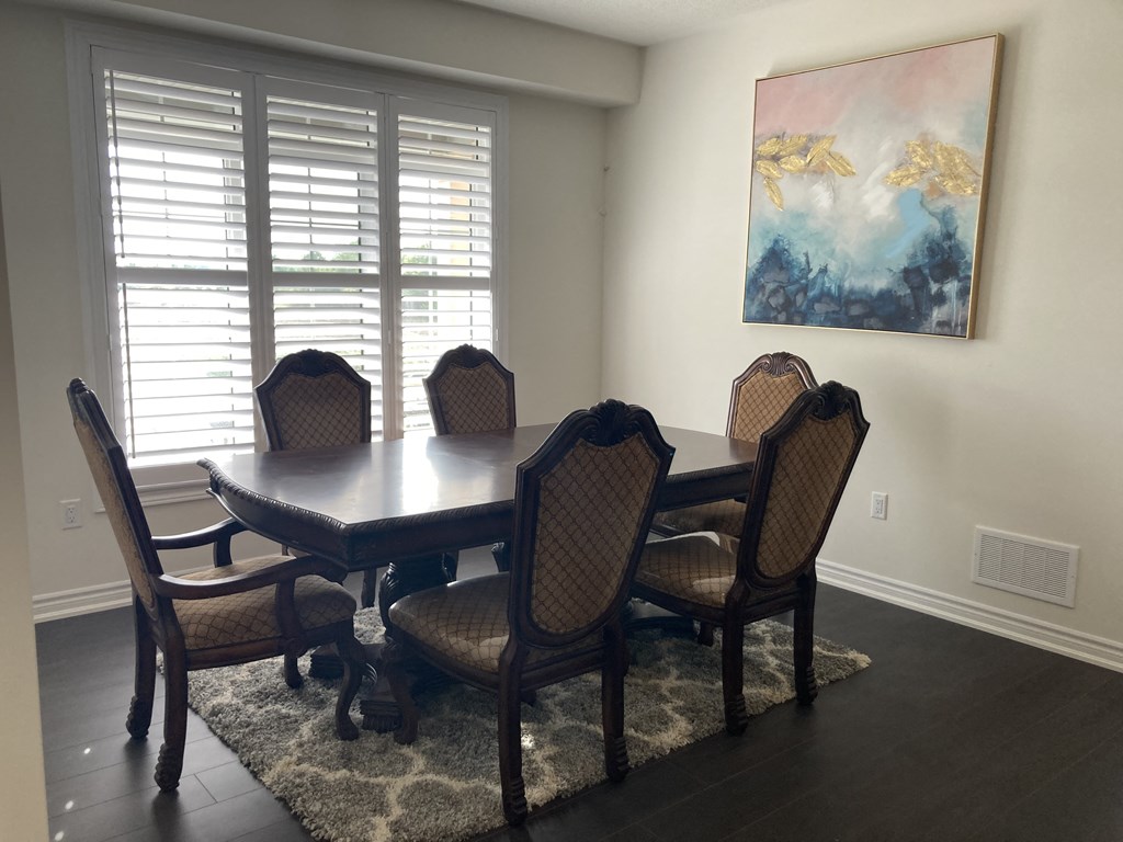 a dining room with a table and chairs and a painting on the wall