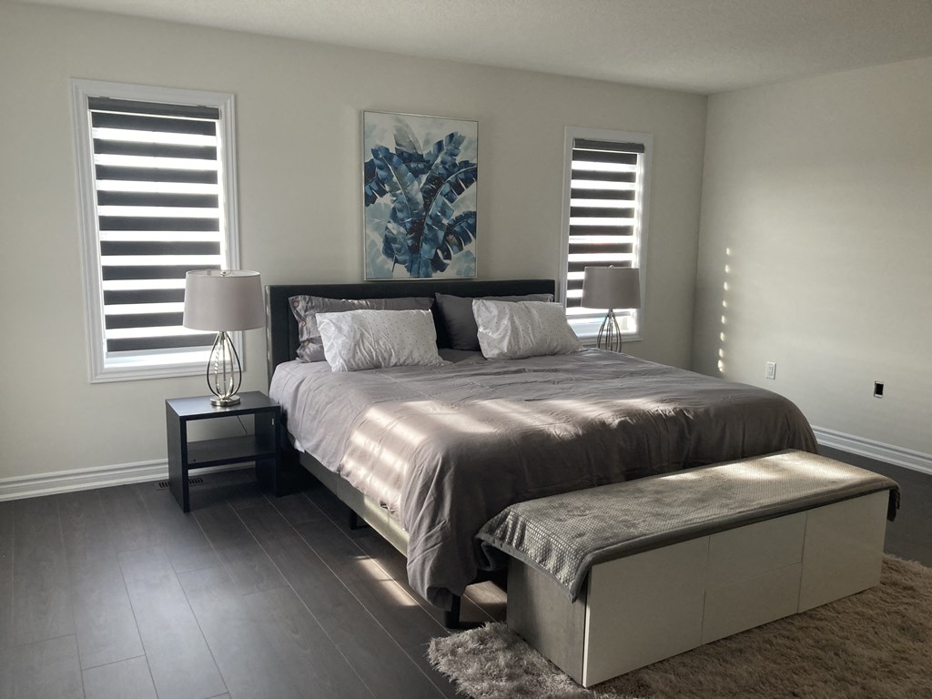 a bedroom with a large bed and two windows