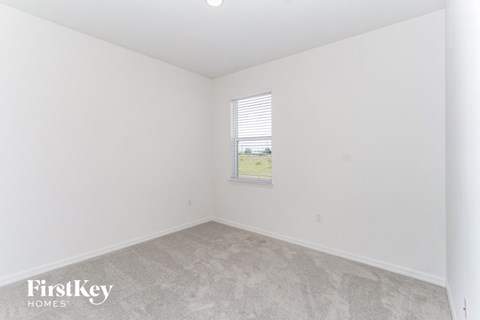 a bedroom with white walls and carpet and a window