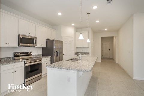 A kitchen with white cabinets and a granite countertop.