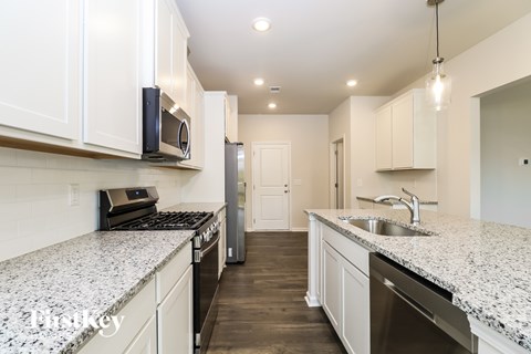 A kitchen with white cabinets and granite countertops.