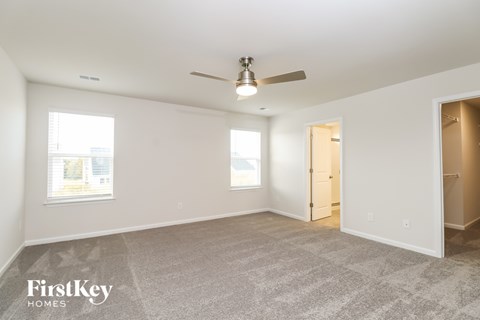 A spacious room with a carpeted floor and a ceiling fan.