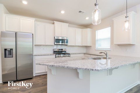 a kitchen with white cabinets and a marble counter top