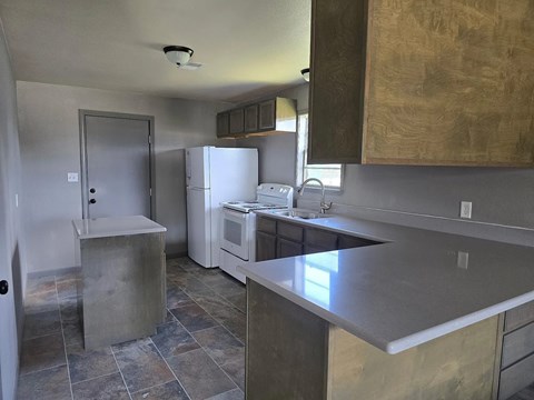 A kitchen with a refrigerator, microwave, and oven.