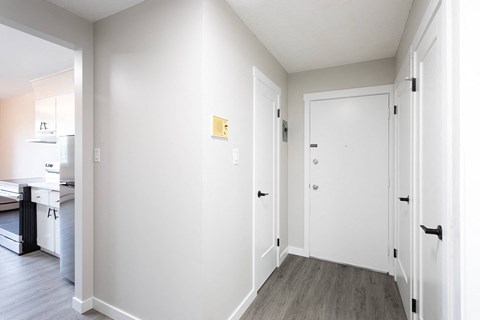 a hallway with white walls and white doors and a wood floor