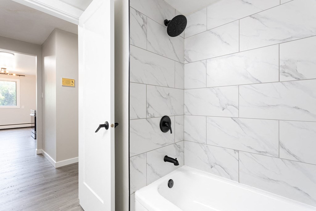 the master bathroom has a tub and a shower with white marble tiles