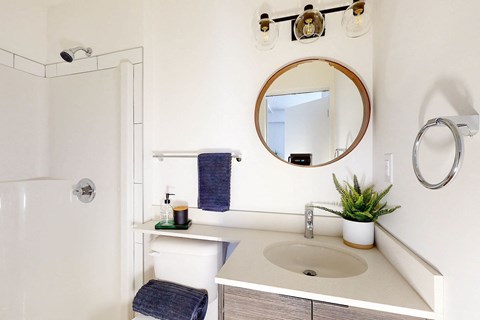 A bathroom with a white sink and a round mirror.