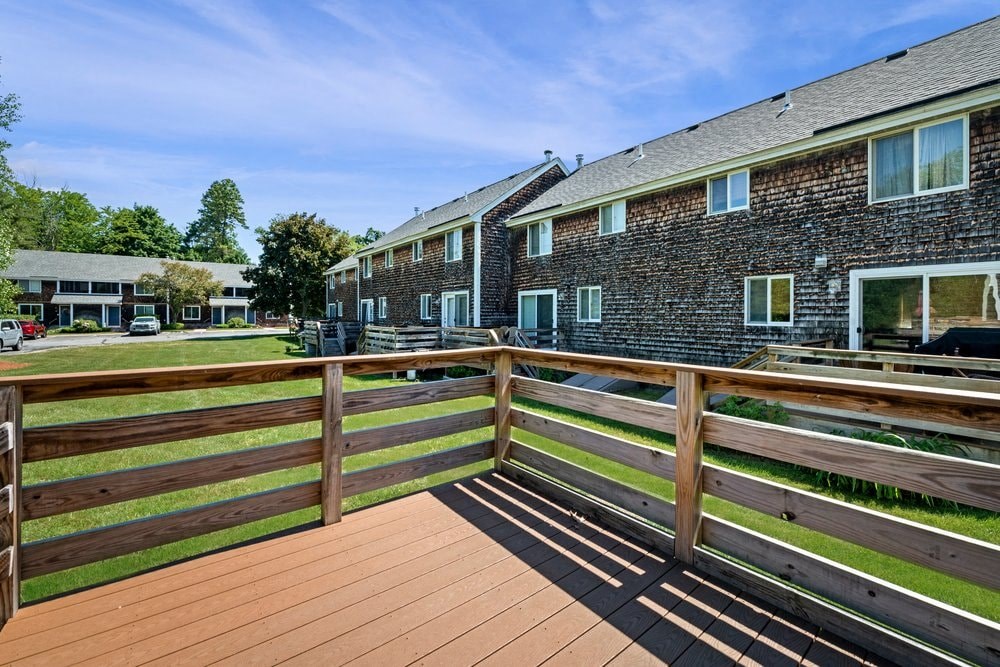 the backyard of a house with a wooden deck