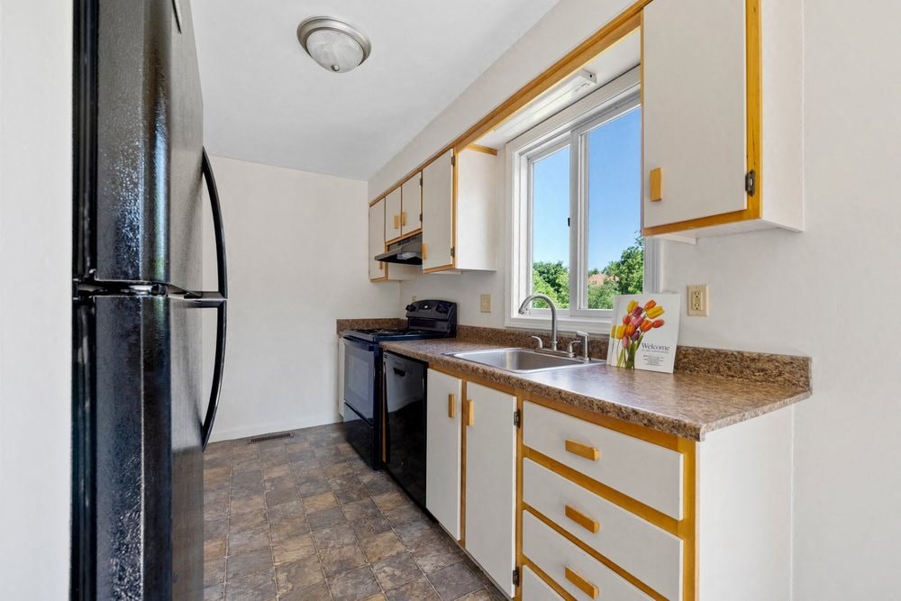 a kitchen with a sink and refrigerator and a window