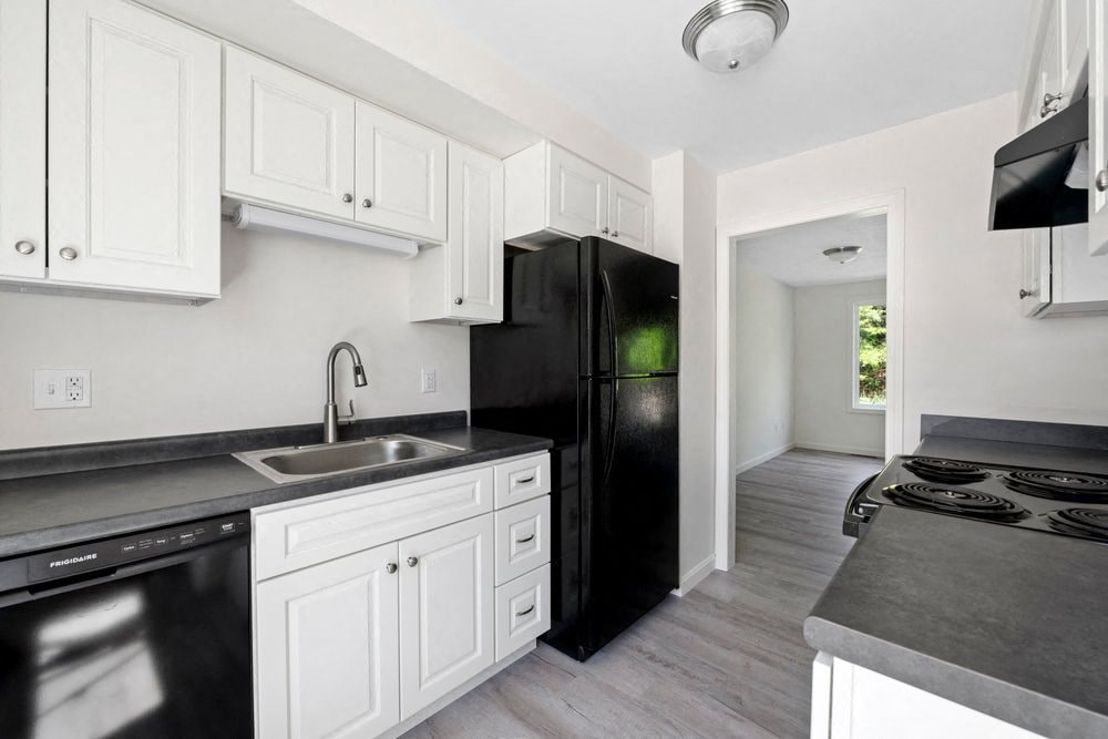 a kitchen with white cabinets and a black refrigerator