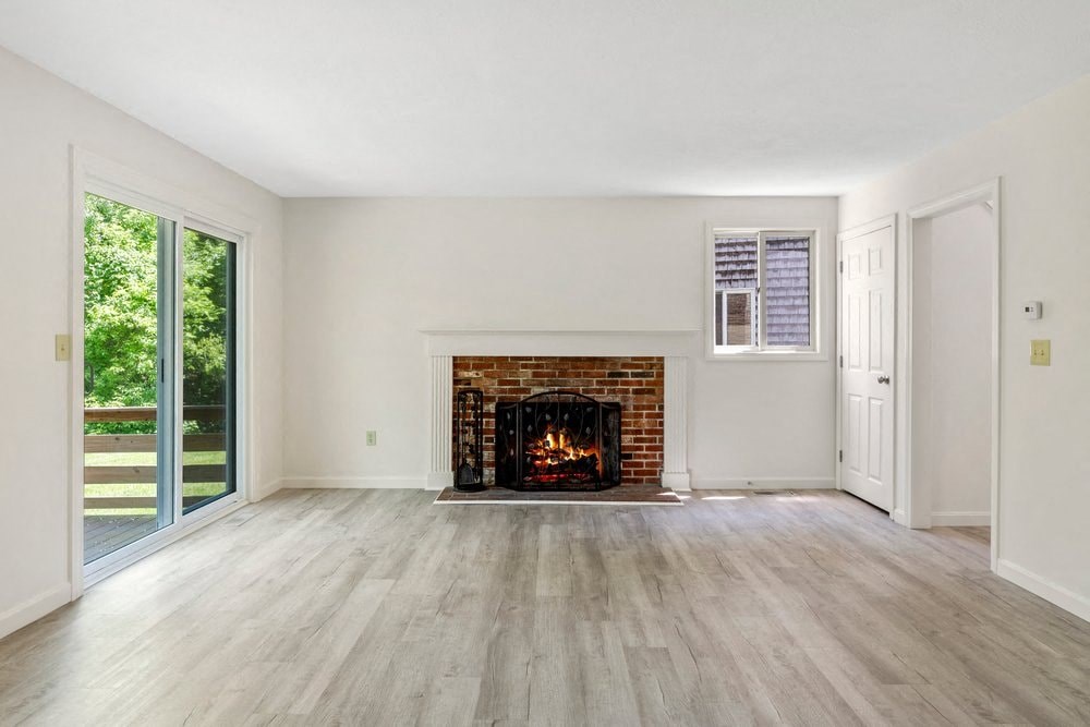 an empty living room with a fireplace and a sliding glass door