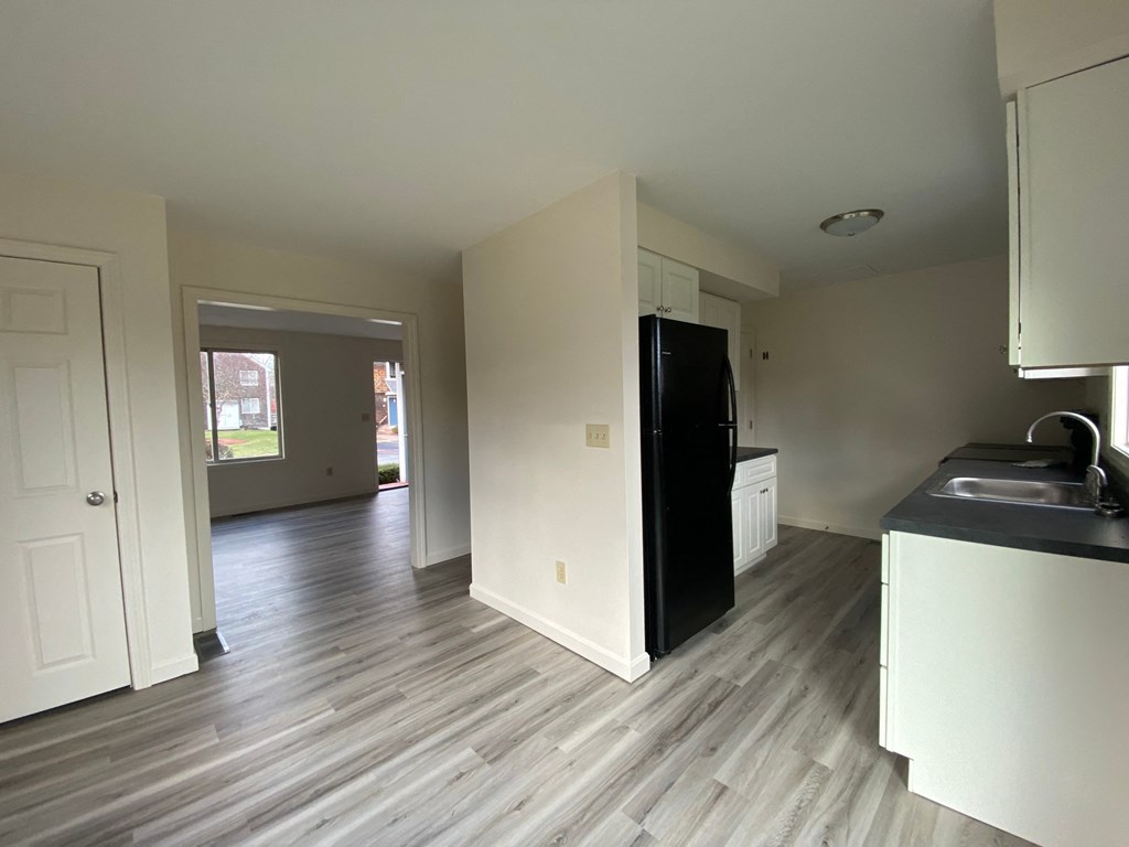 a kitchen and living room with wood floors and a black refrigerator