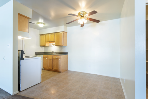 an empty kitchen with a ceiling fan and a white refrigerator