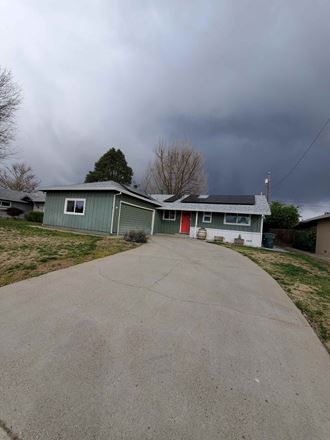 a green house on the side of a road with a cloudy sky