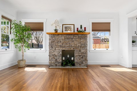 the living room has a stone fireplace and wooden floors