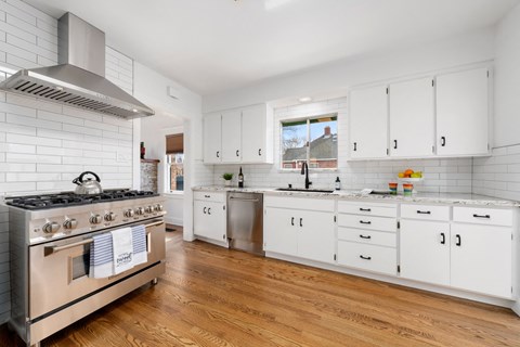 a renovated kitchen with white cabinets and stainless steel appliances