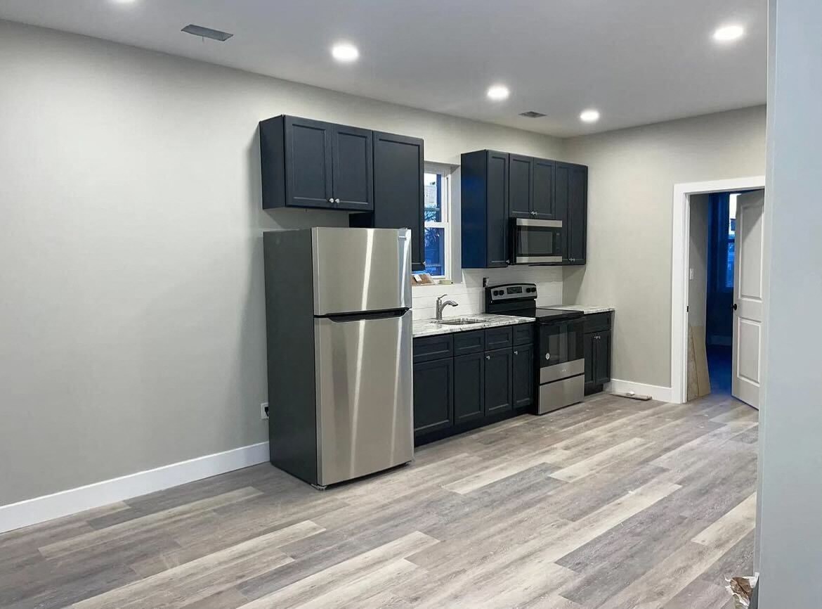 a kitchen with black cabinets and a stainless steel refrigerator