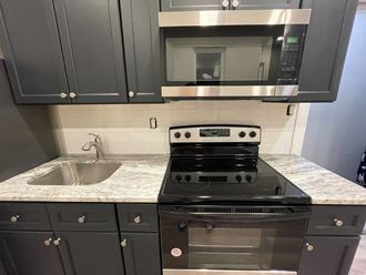 a kitchen with black cabinets and a stove and a sink