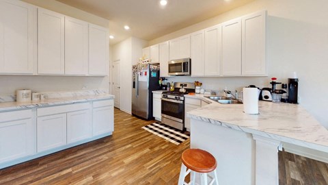 A kitchen with white cabinets and a wooden floor.