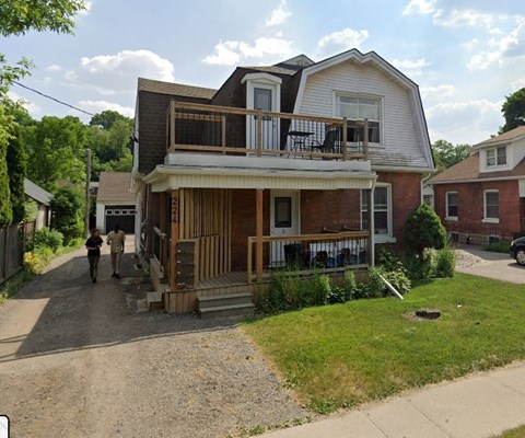 A house with a white and brown exterior and a balcony.