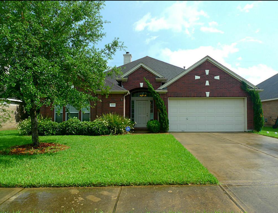 a house with a driveway and a tree in front of it