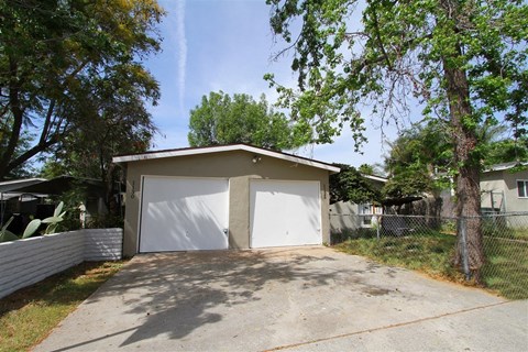 a small garage with a white door and a tree