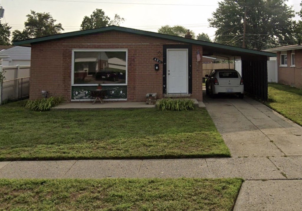 A small house with a white car in the driveway.