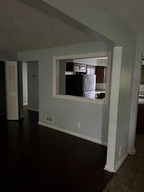 an empty living room with a large window and a kitchen