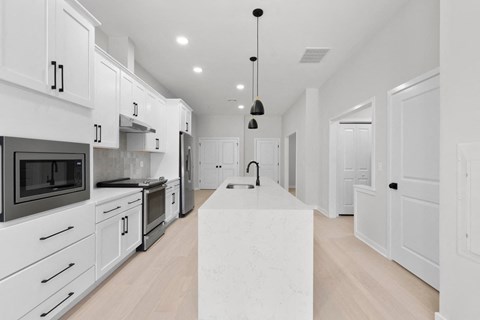 a large kitchen with white cabinets and a marble island