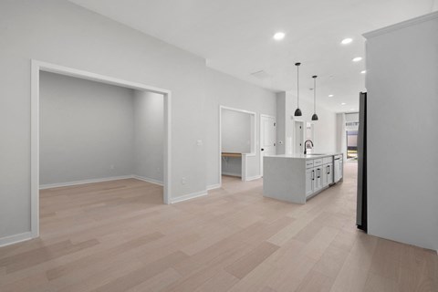 a living room and kitchen with white walls and wood floors