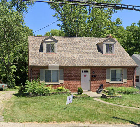 a small brick house with a lawn in front of it