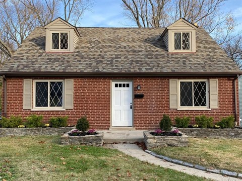 a brick house with a white door and a lawn