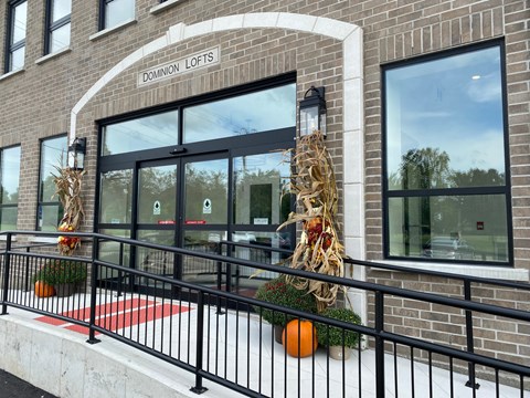 A brick building with a black railing and a sign that says "Dominion Lofts".