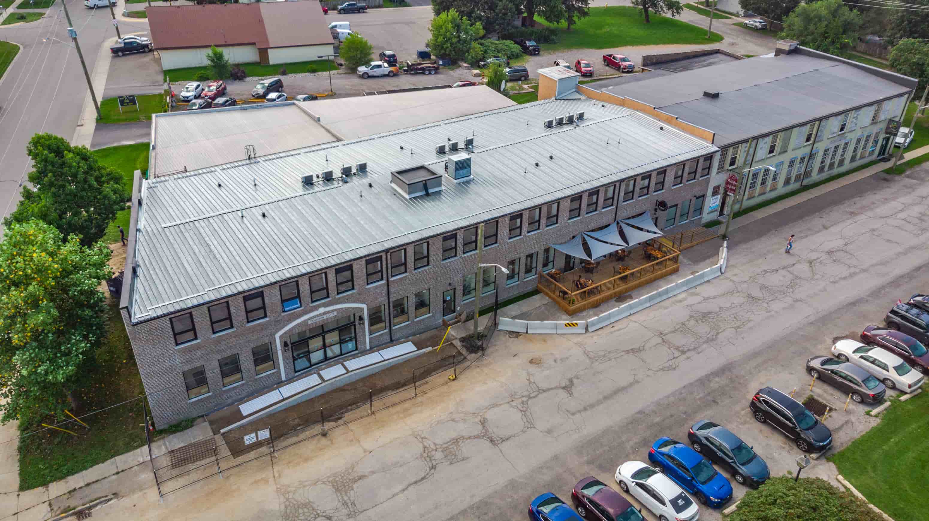 A large grey building with a metal roof and a parking lot in front.