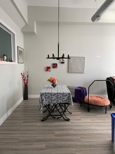 A room with a grey table cloth and a chair with a pink cushion.